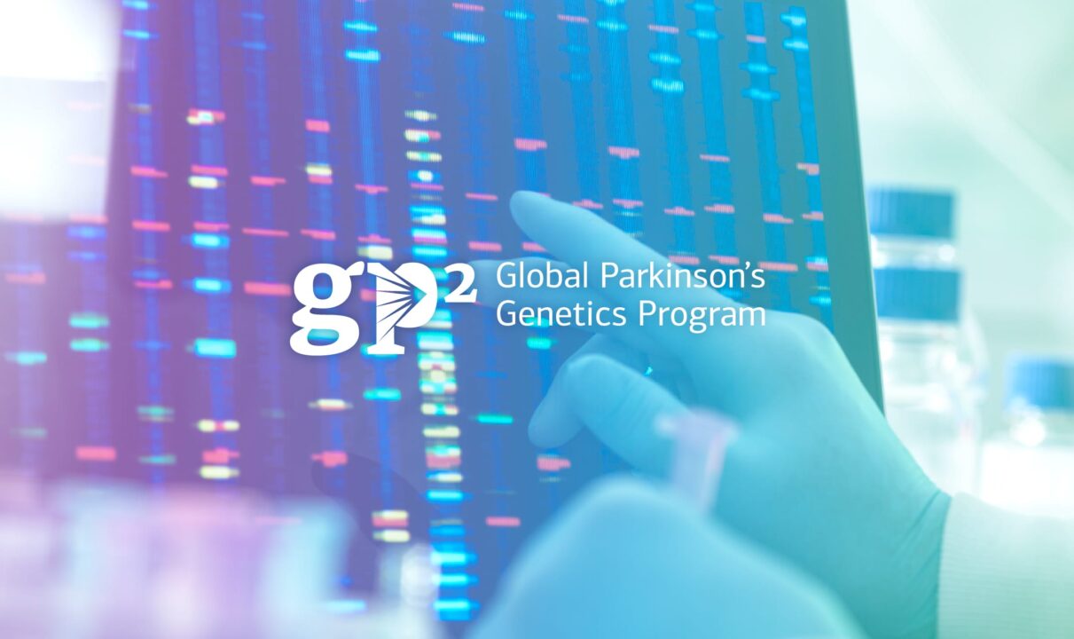 An image featuring the Global Parkinson's Genetics Program (GP2) logo overlaid on a background showing a genetic data visualization, a DNA sequencing readout. A gloved hand is pointing at the data on a screen, indicating a scientific or research setting.