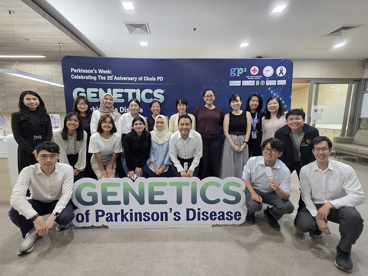 Meeting attendees pose in front of an event backdrop with a Genetics of Parkinson’s Disease sign.